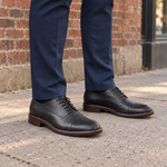 Zapatos negros con modelo y pantalón azul marino